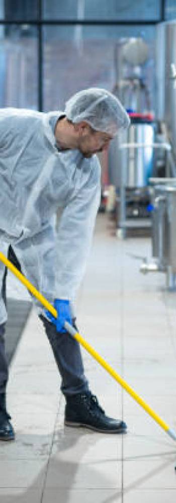 industriservice Professional industrial cleaner in protective uniform cleaning floor of food processing plant. Cleaning services.
